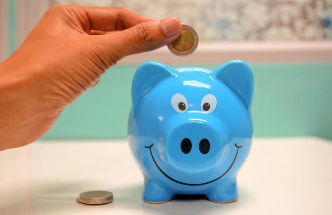 person putting coin in a piggy bank